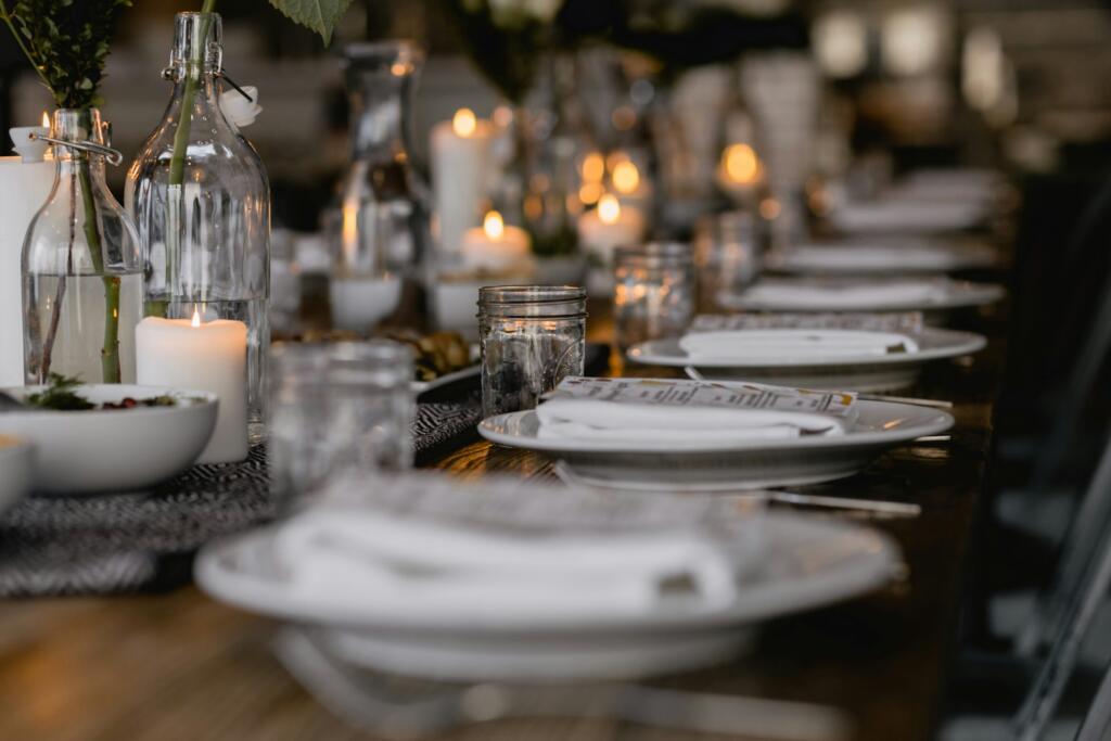 Long dining table set with white plates, candles and glassware