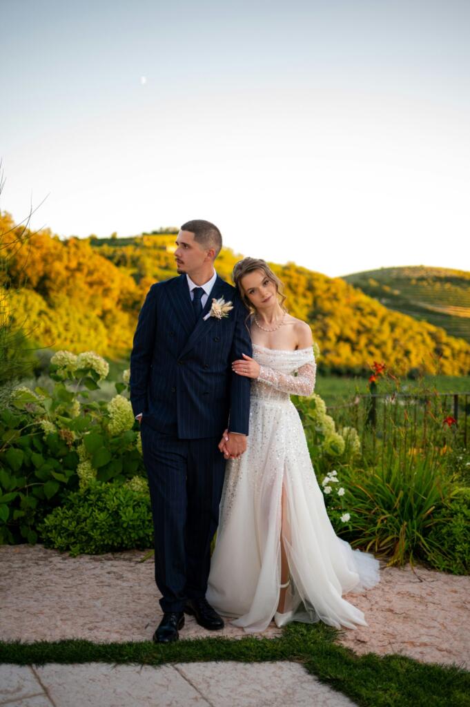 Newlyweds holding hands in a garden at sunset
