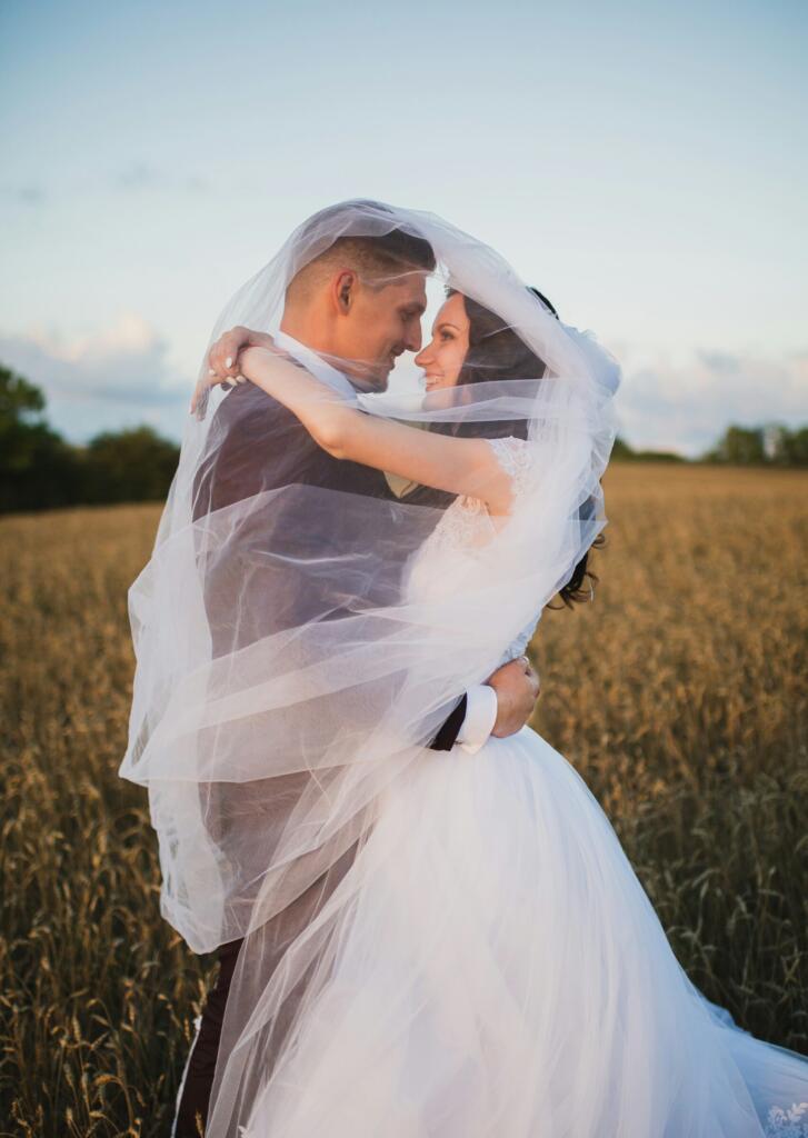 Smiling newly married couple about to kiss in a green field