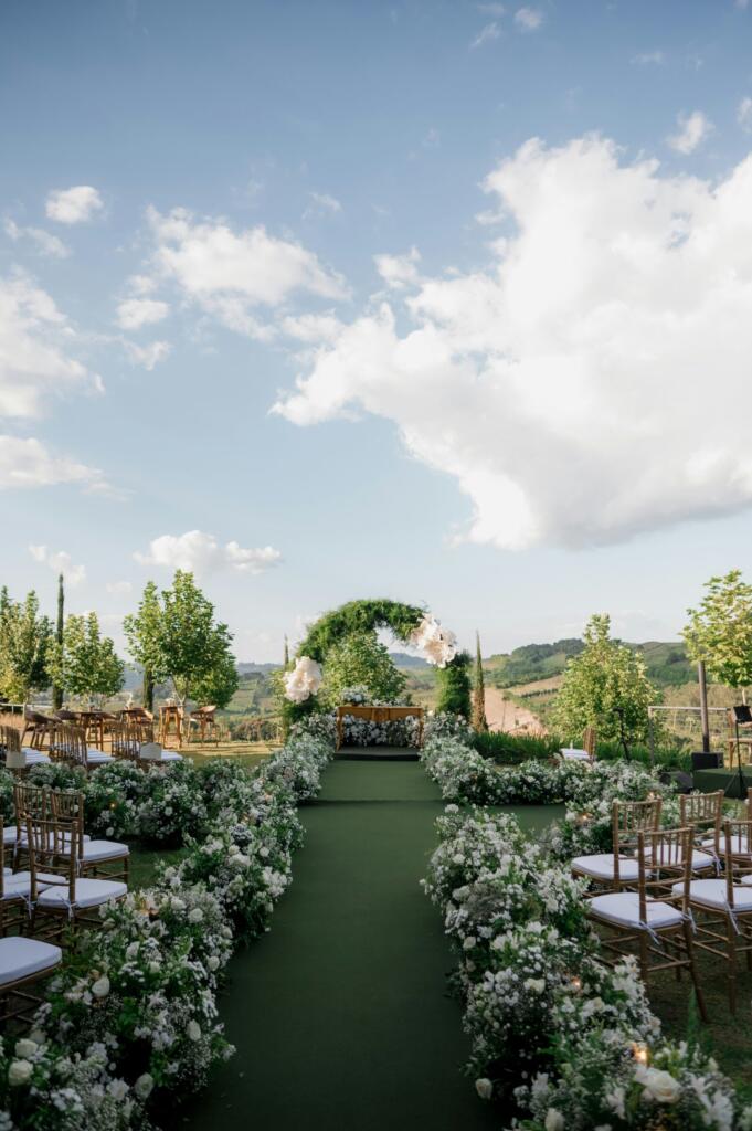 Rows of chairs and floral arrangements set up for an outdoor wedding ceremony